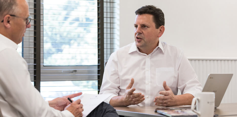 Two men with white shirts discussing business