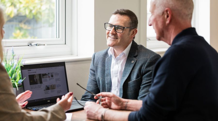 A smiling woman and a man talking on a desk