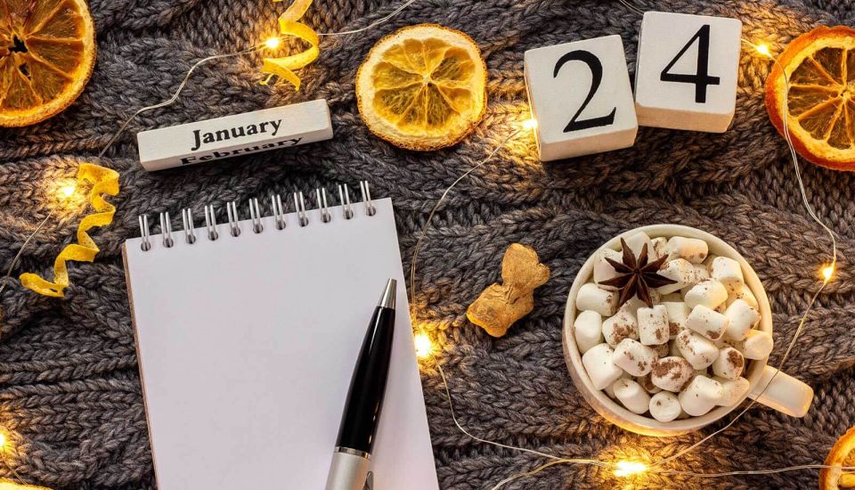 Notepad on a table for 2024 January resolutions next to a cup of chocolate