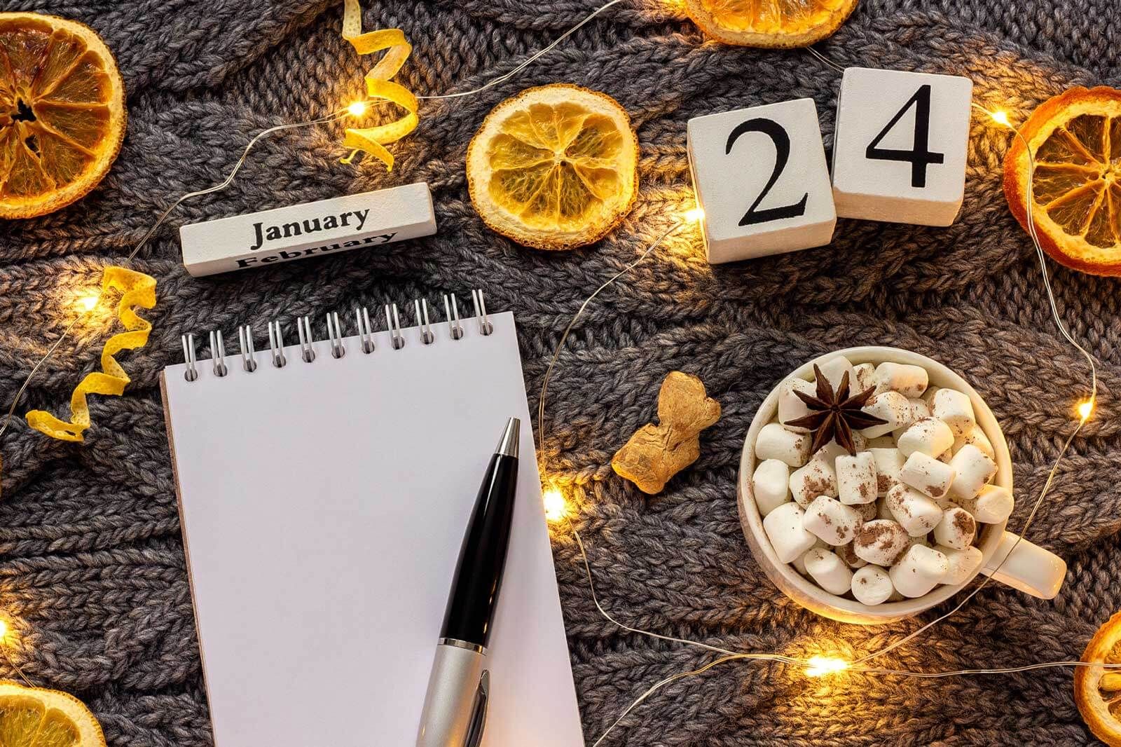 Notepad on a table for 2024 January resolutions next to a cup of chocolate