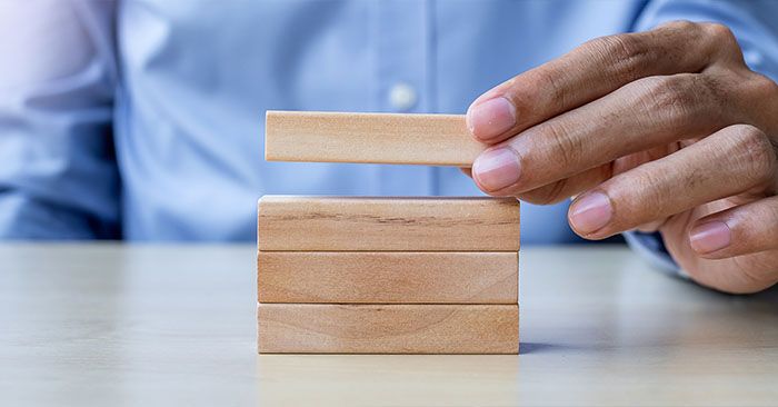 a person building a tower of wooden blocks