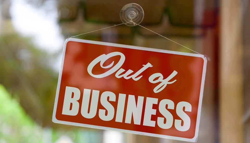 Closeup of a red sign on a window shop displaying an out-business message